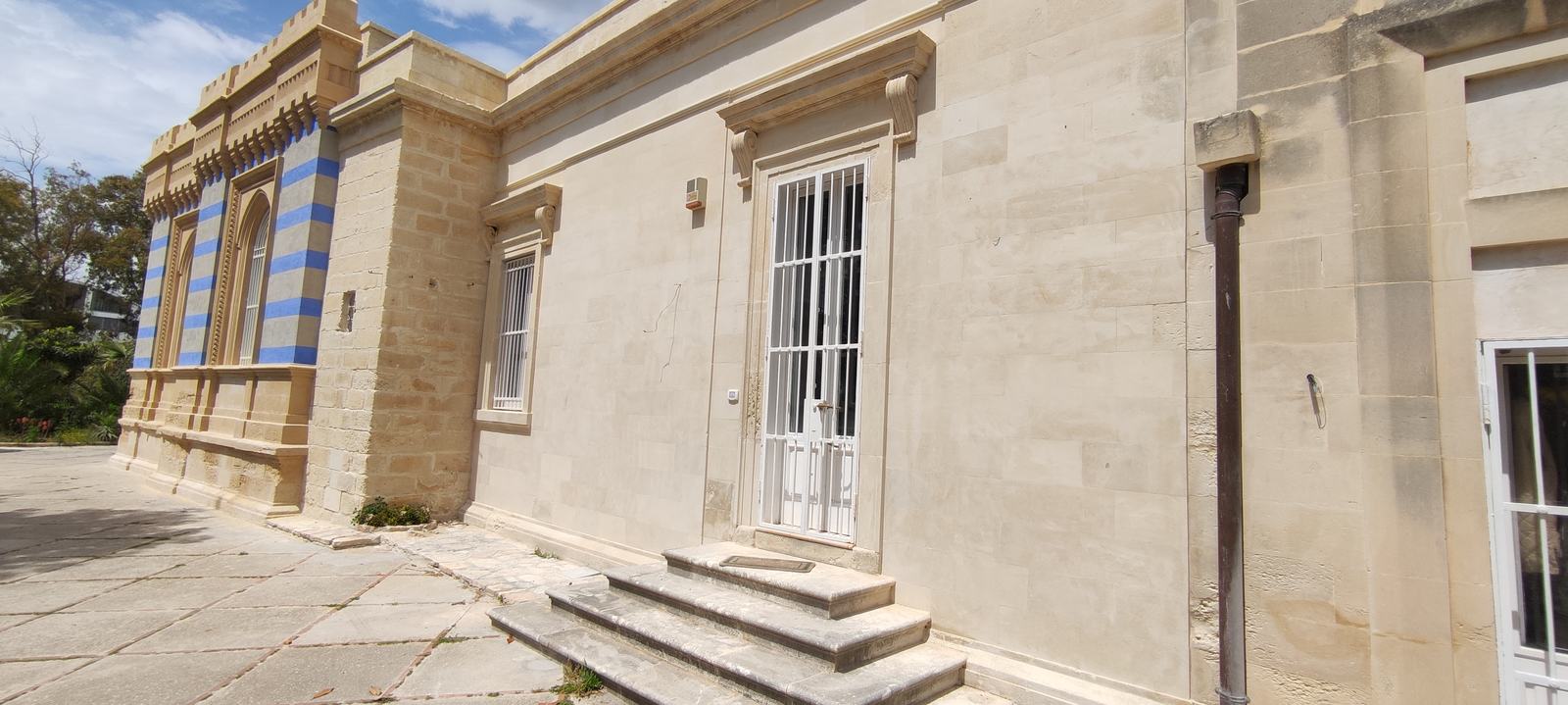 Villa Arabesca dopo il restauro: prospetto laterale in pietra chiara con gradini e finestre alte con telaio bianco
